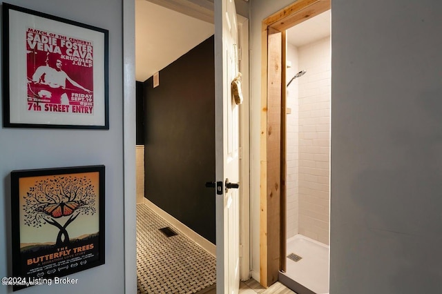 bathroom with tile patterned flooring and a tile shower