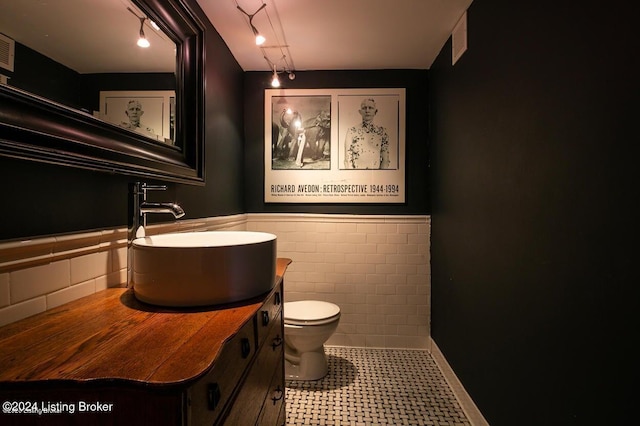 bathroom with tile patterned flooring, vanity, toilet, and tile walls