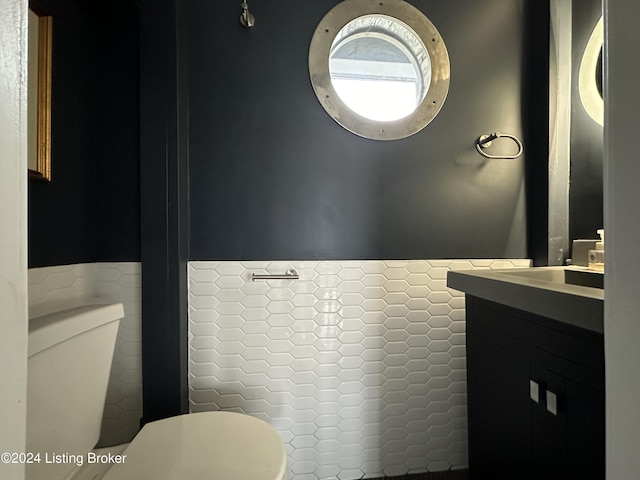 bathroom featuring vanity, tile walls, and toilet