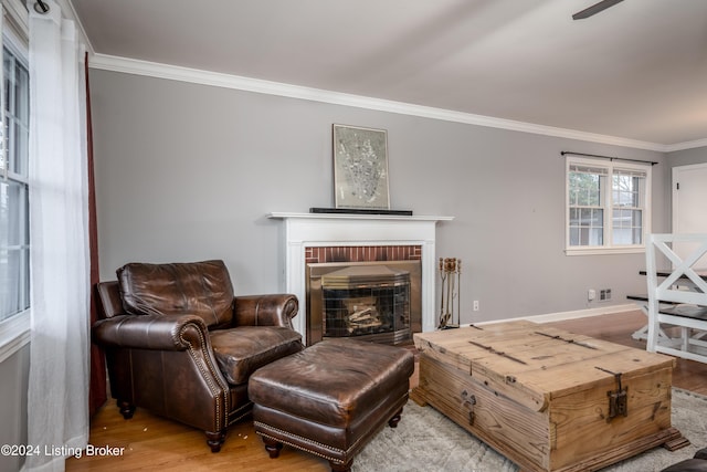 living room with a brick fireplace, wood-type flooring, and ornamental molding