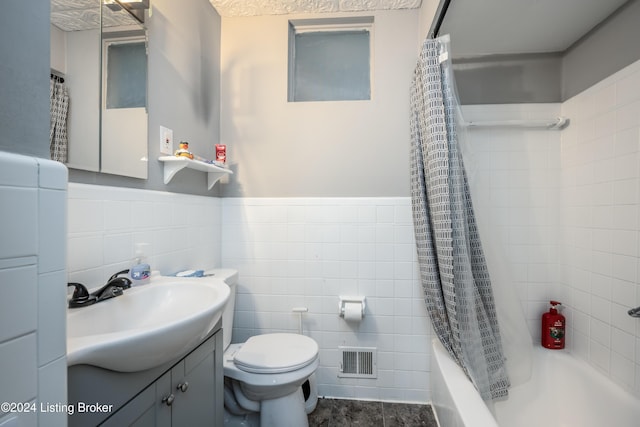 full bathroom with shower / bath combo, vanity, toilet, and tile walls