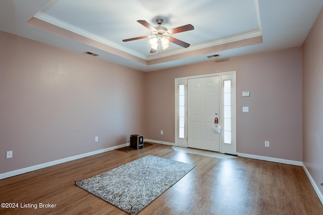 entrance foyer featuring a tray ceiling, crown molding, and light hardwood / wood-style floors