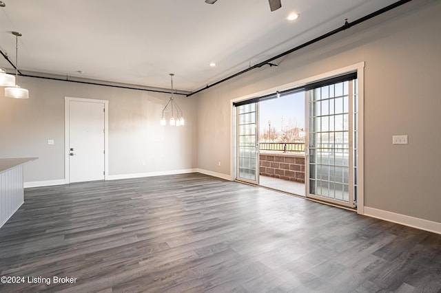 spare room featuring dark wood-type flooring and a notable chandelier