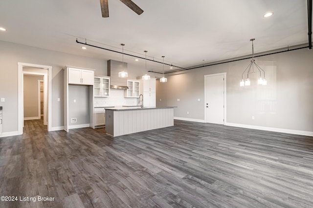 unfurnished living room with ceiling fan, sink, rail lighting, and dark hardwood / wood-style floors