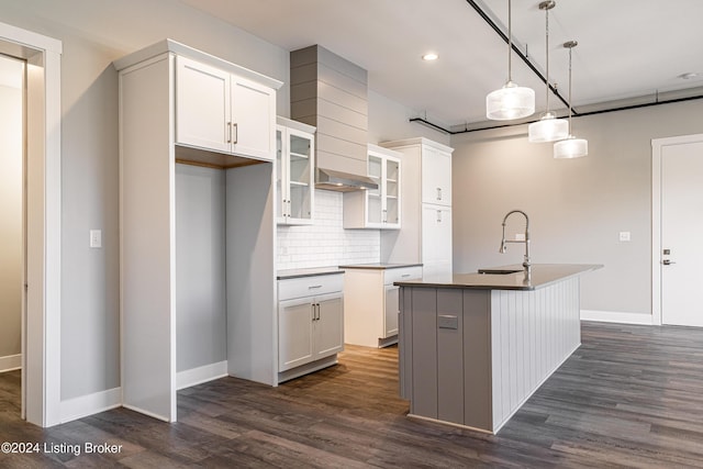 kitchen with white cabinetry, a kitchen island with sink, sink, and dark wood-type flooring