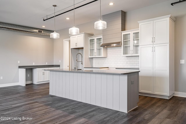 kitchen with a center island with sink, dark hardwood / wood-style floors, pendant lighting, and white cabinetry