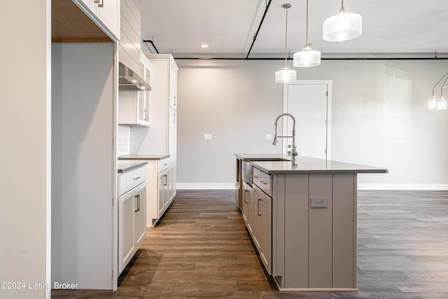 kitchen featuring white cabinetry, dark hardwood / wood-style flooring, an island with sink, and hanging light fixtures