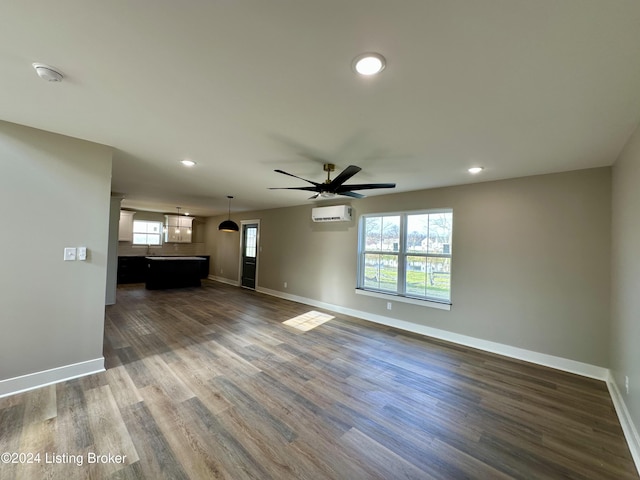 unfurnished living room featuring dark hardwood / wood-style floors, an AC wall unit, a wealth of natural light, and ceiling fan