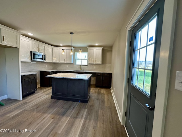 kitchen featuring sink, white cabinets, hardwood / wood-style floors, a kitchen island, and hanging light fixtures