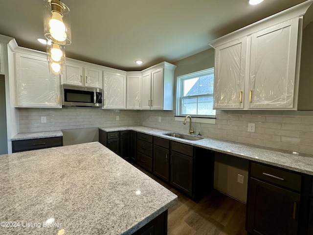 kitchen with dark hardwood / wood-style flooring, tasteful backsplash, sink, pendant lighting, and white cabinetry