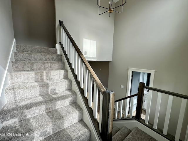 stairway with a high ceiling and a notable chandelier