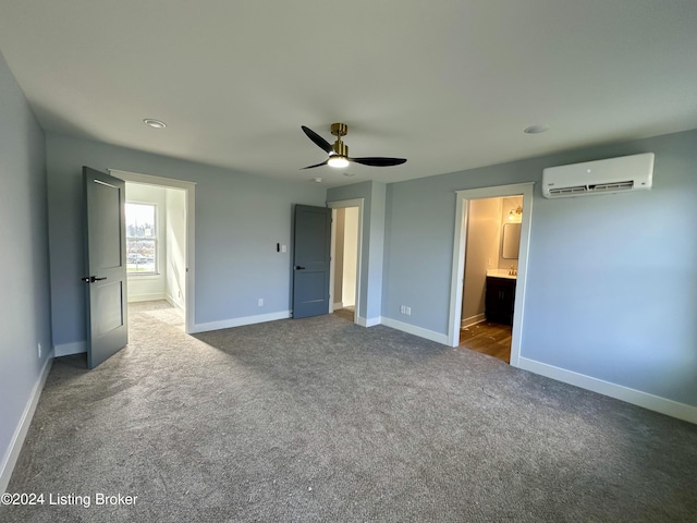 unfurnished bedroom with a wall mounted air conditioner, ceiling fan, carpet floors, and connected bathroom