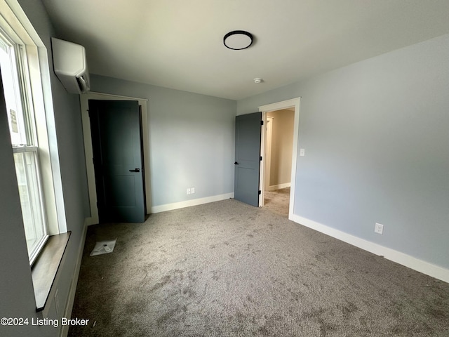 unfurnished bedroom with a wall unit AC and carpet floors