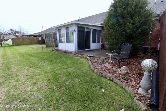 rear view of house with a lawn and a sunroom