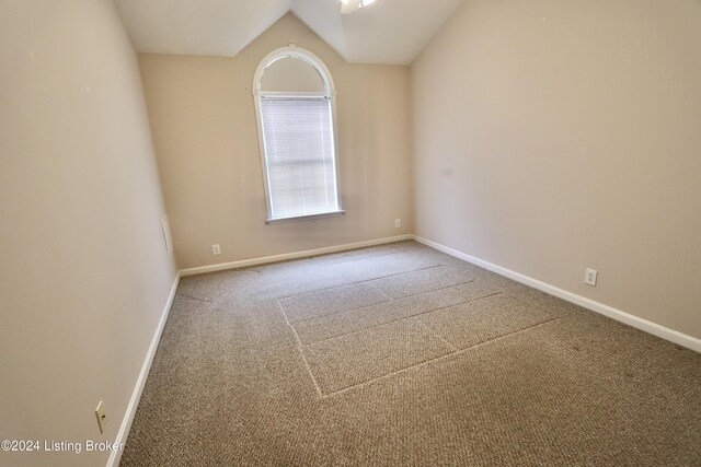 carpeted spare room with vaulted ceiling