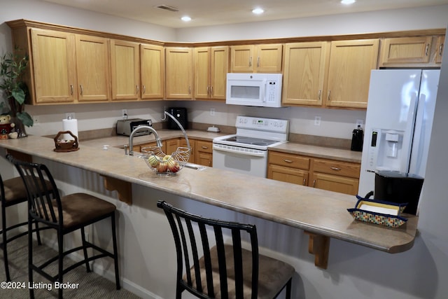 kitchen featuring kitchen peninsula, a breakfast bar, white appliances, and sink