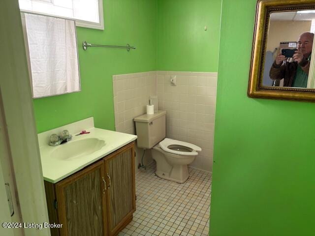 bathroom featuring tile patterned flooring, vanity, toilet, and tile walls