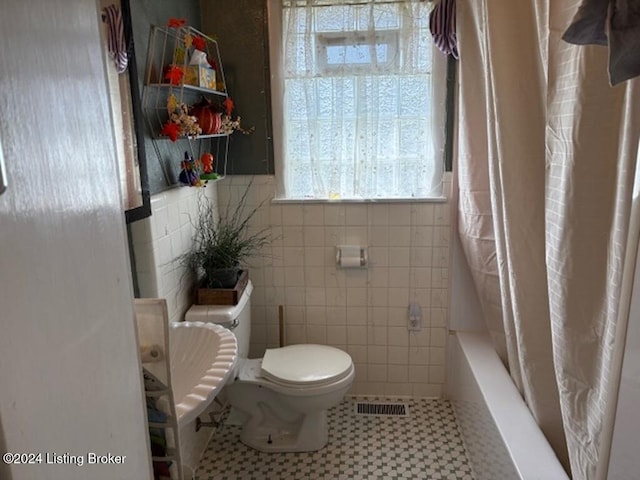 bathroom featuring shower / bath combo with shower curtain, tile patterned flooring, tile walls, and toilet