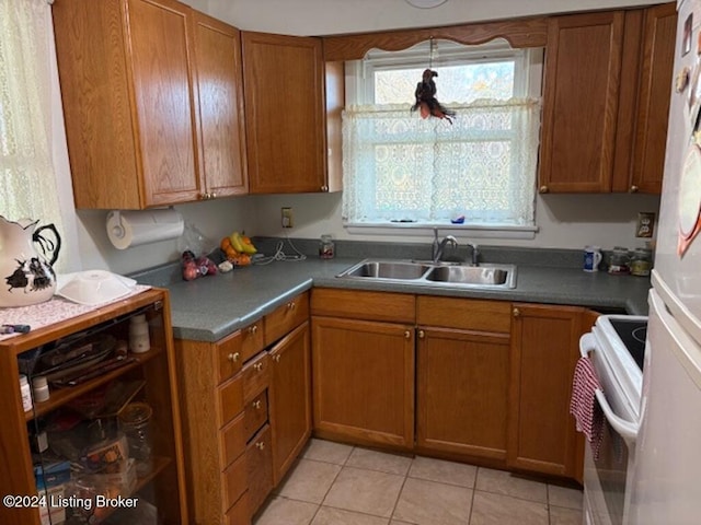 kitchen featuring sink, light tile patterned floors, white fridge, and stove