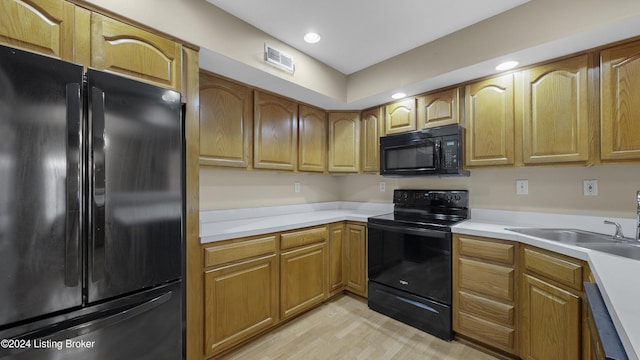 kitchen featuring black appliances, light hardwood / wood-style floors, and sink