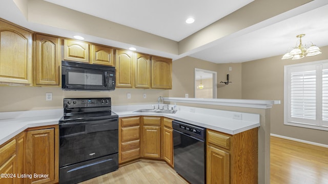 kitchen featuring pendant lighting, black appliances, light wood-type flooring, and a notable chandelier