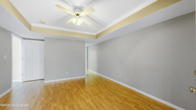 unfurnished room with a raised ceiling, hardwood / wood-style flooring, and ornamental molding