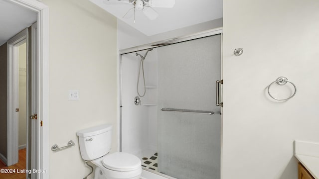 bathroom with ceiling fan, hardwood / wood-style floors, toilet, vanity, and a shower with shower door