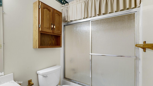 bathroom with enclosed tub / shower combo and toilet