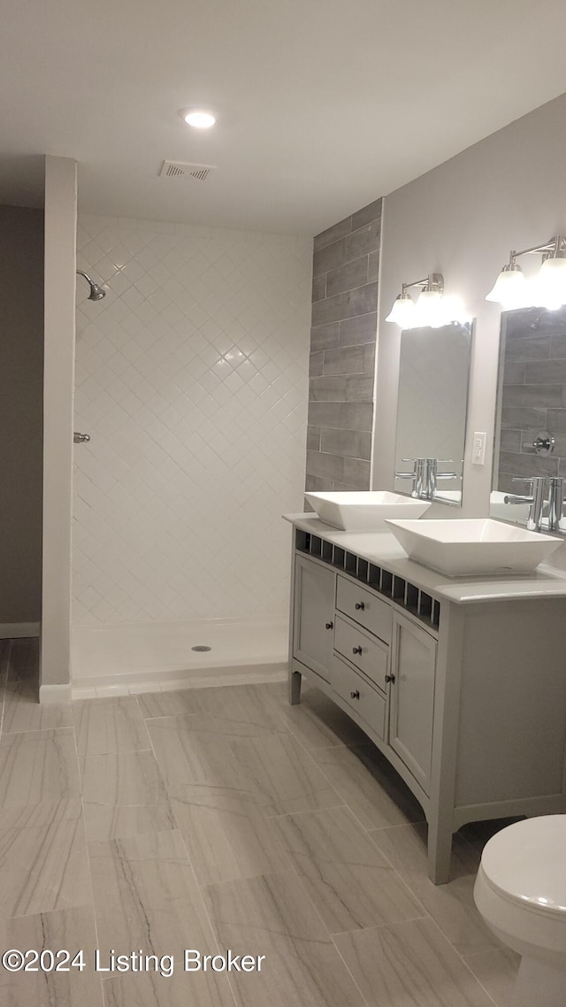 bathroom with a tile shower, vanity, and toilet