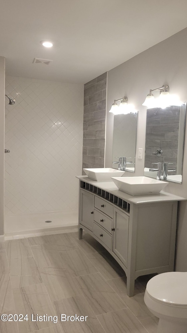 bathroom with tiled shower, vanity, and toilet