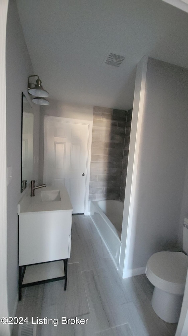 bathroom featuring a bathing tub, vanity, and toilet