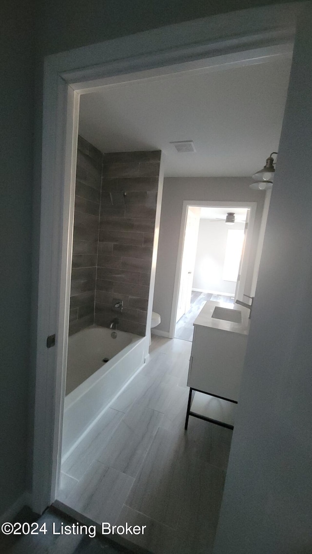 full bathroom with vanity, tiled shower / bath combo, and toilet