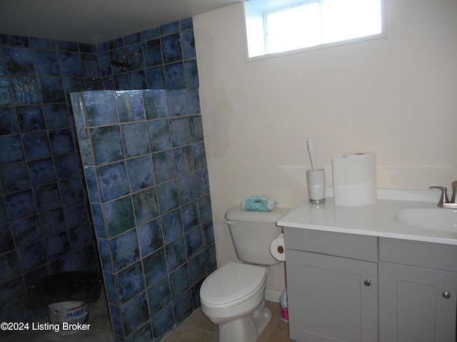 bathroom featuring tile patterned flooring, vanity, toilet, and a tile shower