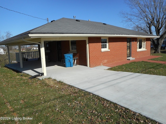 back of house with a carport and a yard