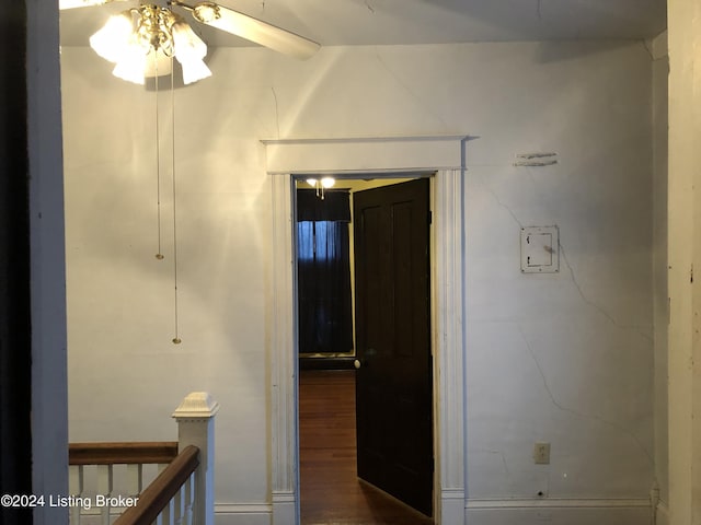 hall with dark wood-style floors and an upstairs landing