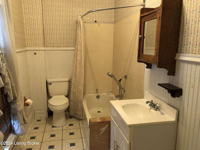 bathroom with wallpapered walls, wainscoting, toilet, tile patterned floors, and shower / bath combo with shower curtain