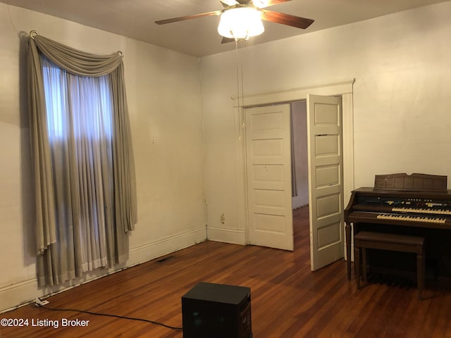 interior space featuring dark wood-type flooring, baseboards, and a ceiling fan