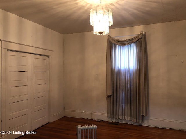 interior space featuring a chandelier, baseboards, radiator heating unit, and wood finished floors