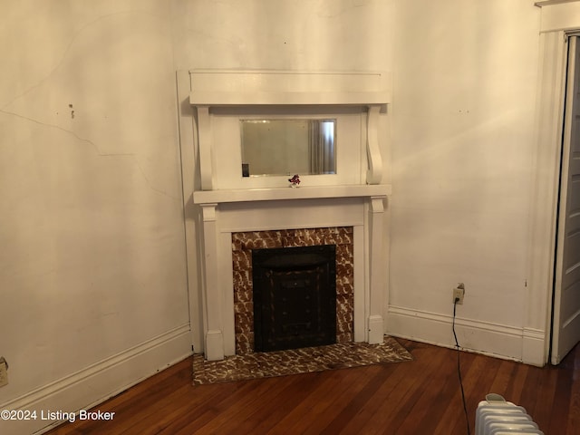 unfurnished living room featuring baseboards, hardwood / wood-style floors, a high end fireplace, and radiator