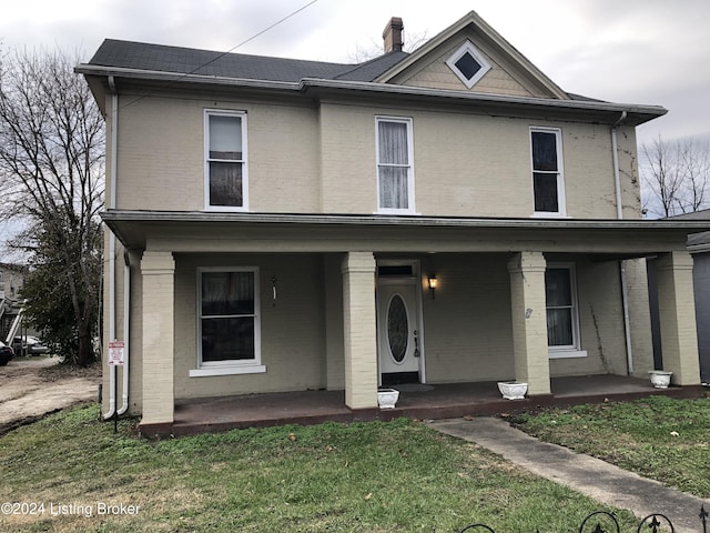 view of front of house with a porch, a front lawn, and brick siding