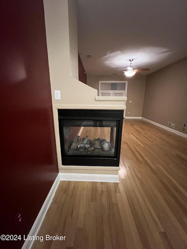 interior details featuring a multi sided fireplace, ceiling fan, and hardwood / wood-style floors