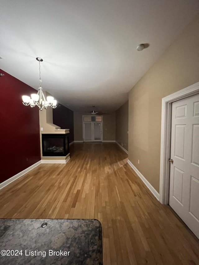 unfurnished living room with wood-type flooring and a notable chandelier