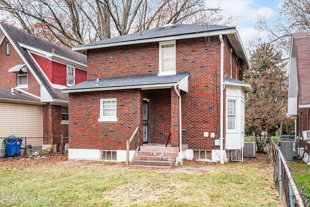 rear view of property featuring a lawn and central air condition unit