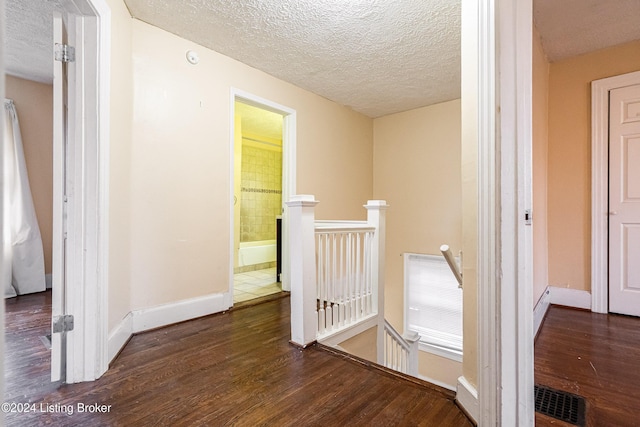 hallway featuring a textured ceiling and dark hardwood / wood-style floors