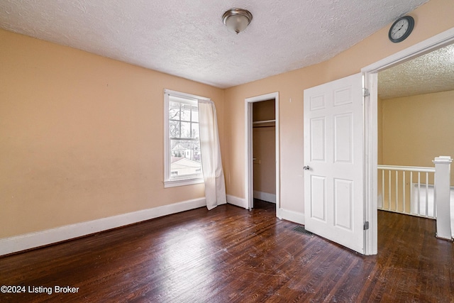 unfurnished bedroom with a textured ceiling, dark hardwood / wood-style flooring, and a closet