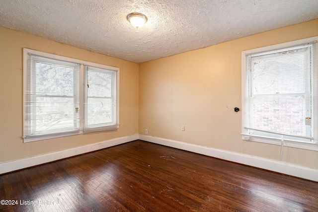 unfurnished room with a textured ceiling and dark wood-type flooring