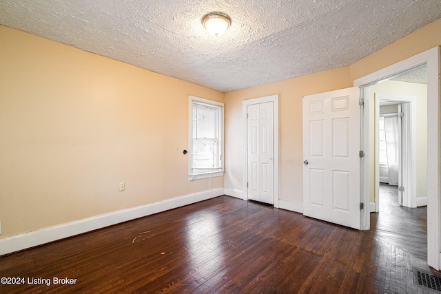 unfurnished bedroom with a textured ceiling and dark hardwood / wood-style floors