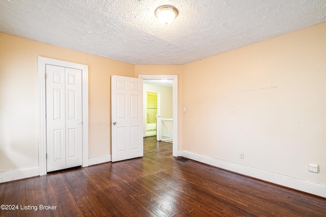 unfurnished bedroom with a textured ceiling, dark hardwood / wood-style flooring, and a closet