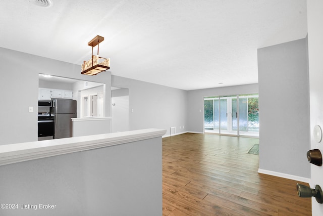 interior space with kitchen peninsula, appliances with stainless steel finishes, pendant lighting, hardwood / wood-style flooring, and white cabinets