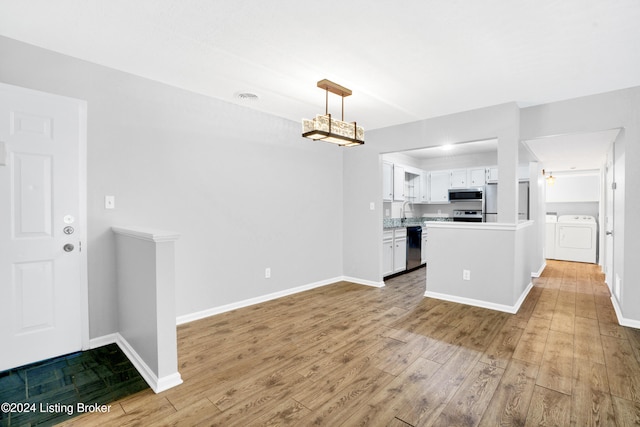 kitchen with wood-type flooring, decorative light fixtures, white cabinets, washer and dryer, and appliances with stainless steel finishes